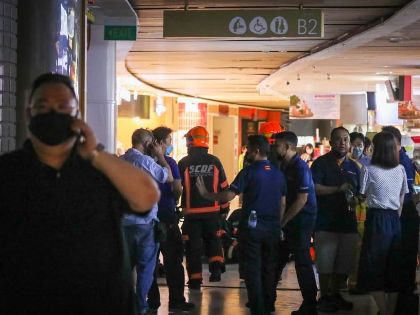 Police and firefighters seen at the second basement level of VivoCity mall, where a fire led to workers from about a dozen shops and food stalls being evacuated on June 7, 2022. 