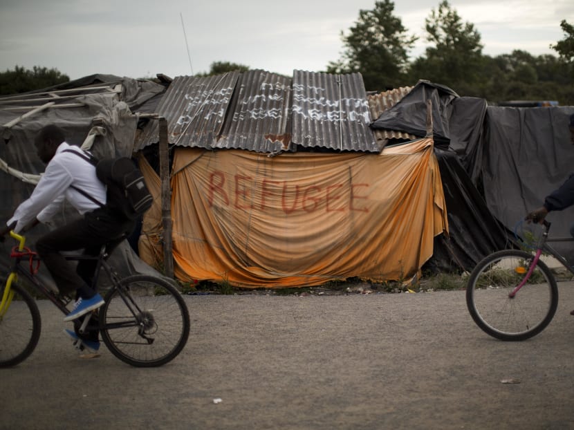 Migrants ride bicycles past tents a camp set near Calais, northern France, Wednesday, Aug 5, 2015. Photo: AP