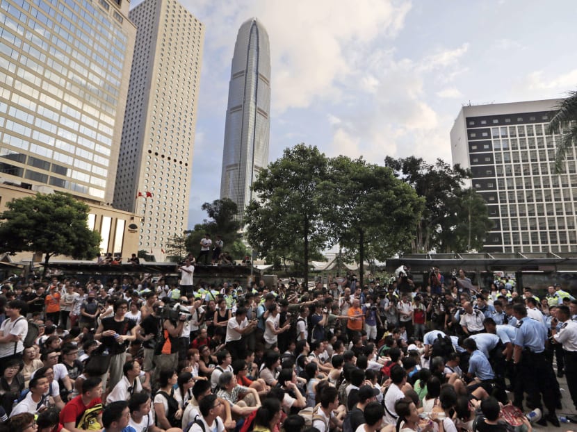 In this July 2, 2014 photo, protesters are taken away by police officers after hundreds of protesters staged a peaceful sit-ins overnight on a street in the financial district in Hong Kong. Photo: AP