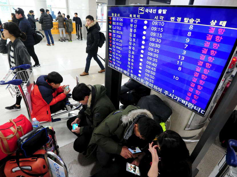 Passengers gather around a TV screen showing cancelled domestic flights at Jeju International Airport on Jeju island, South Korea, Jan 24, 2016. Photo: Reuters