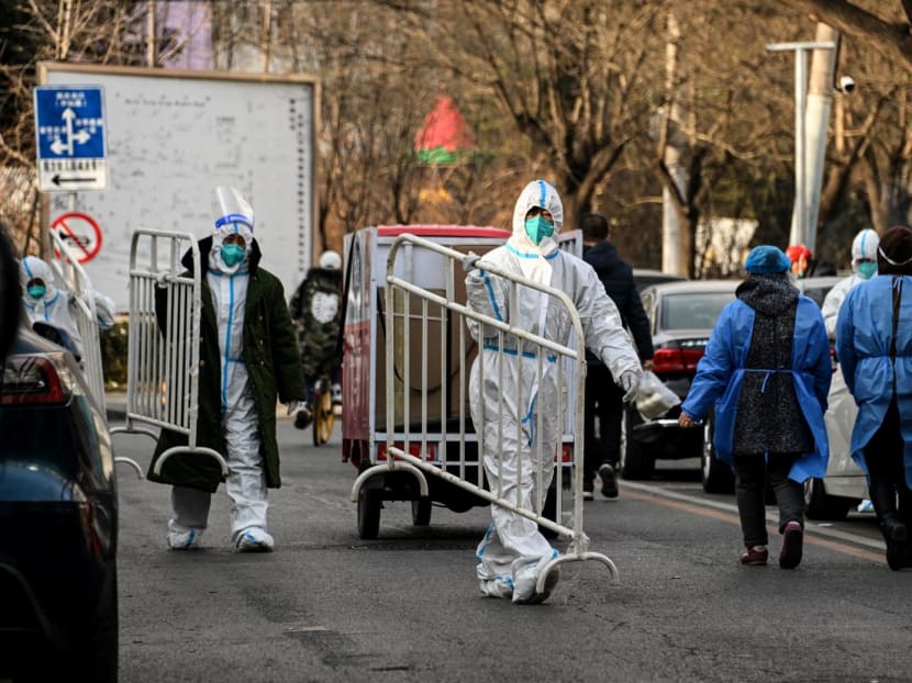 Health workers wearing personal protective equipment carry barricades inside a residential community that just opened after a lockdown due to Covid-19 coronavirus restrictions in Beijing on Dec 9, 2022.
