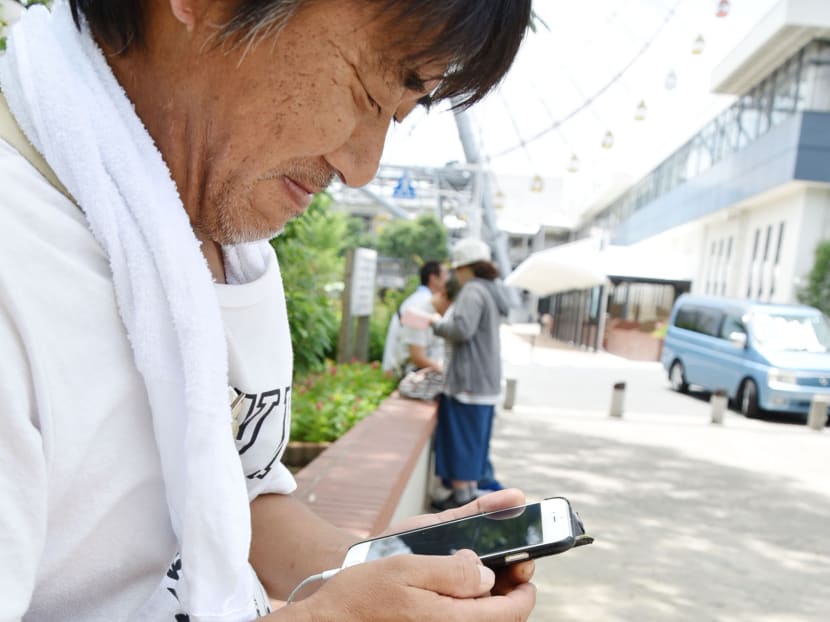 Mr Tsutomu Misago, 48, playing Pokemon Go on his smartphone in Tempozan Park, Osaka. Photo: Kyodo News