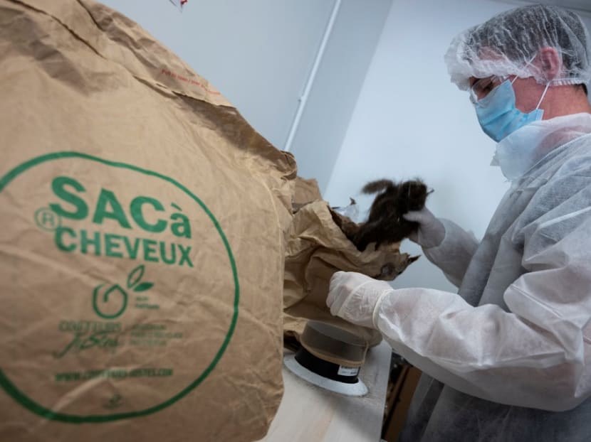 A worker fills paper bags with hairs received from hairdressers in France and used to make hydrocarburant absorbent draft snake in Brignoles, southeastern France.