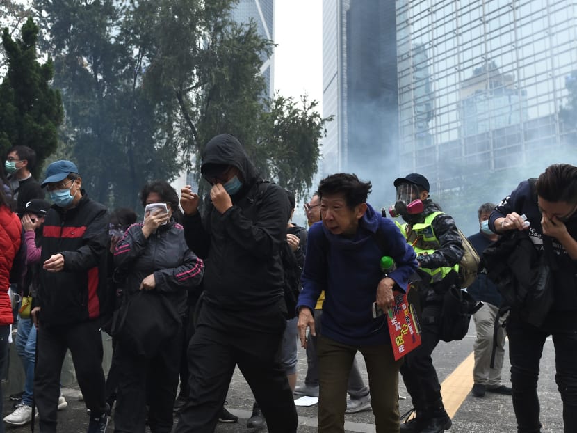 People react to tear gas fired by police to disperse the crowd gathered for the 'universal siege on communists' rally at Chater Garden in Hong Kong on Jan 19, 2020.