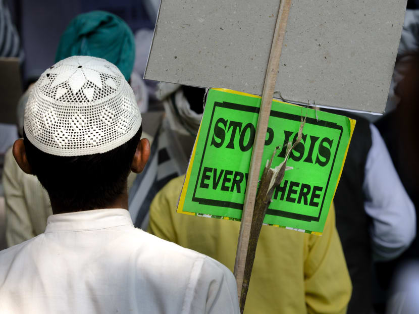 An Indian Muslim man holds a banner and listens to a speaker during a protest against ISIS, an Islamic State group, and Friday's Paris attacks, in New Delhi, India, on Nov 18, 2015. Photo: AP