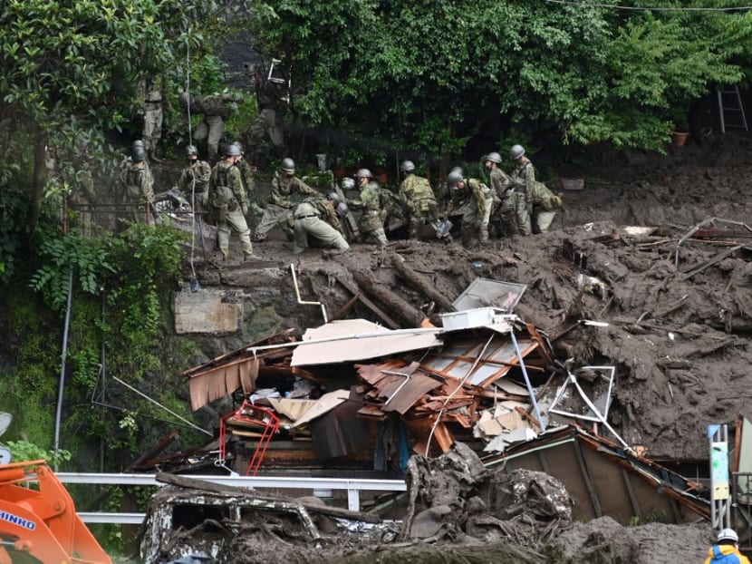 Members of Japan's Self-Defense Forces sift through mud and debris as they search for missing people at the scene of a landslide in Atami, Shizuoka Prefecture, on July 5, 2021.