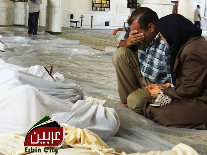 A man and woman mourn over the dead bodies of Syrian men after an alleged poisonous gas attack fired by regime forces. Photo: AP/Local Committee of Arbeen
