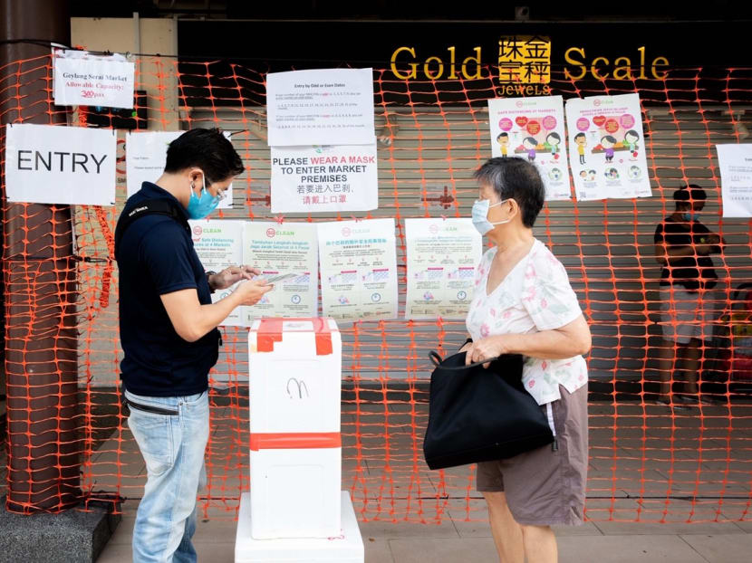 An officer checks the National Registration Identity Card of a shopper before allowing her to enter Geylang Serai Market on Friday (April 24). An officer checks the National Registration Identity Card of a shopper before allowing her to enter Geylang Serai Market on Friday (April 24).