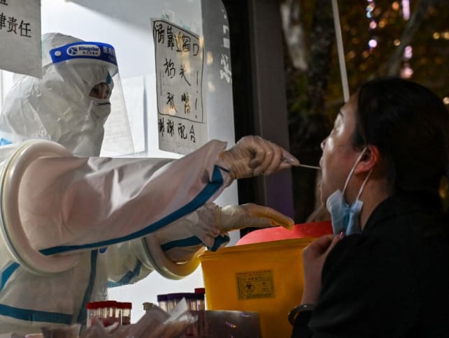 A health worker takes a swab sample from a woman to test for the Covid-19 coronavirus in the Jing'an district in Shanghai on Nov 28, 2022.