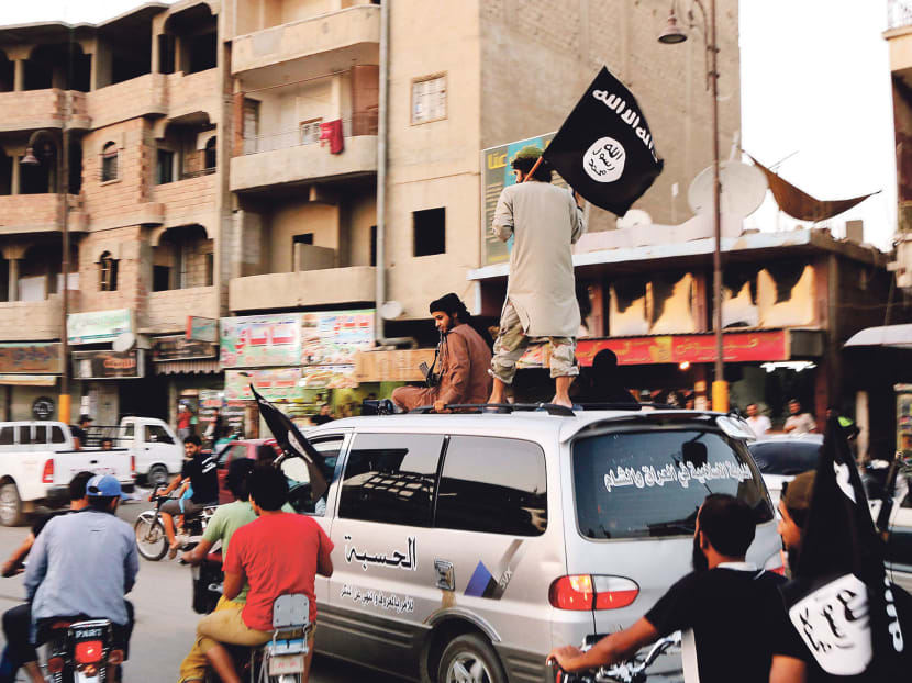 Members loyal to the Islamic State in Iraq and the Levant (ISIL) wave ISIL flags as they drive around Raqqa June 29, 2014. Photo: Reuters