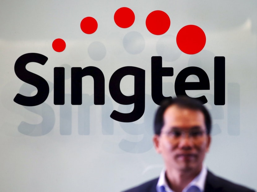 A Singtel executive passes a Singtel logo at their head office in Singapore on April 8, 2015. Photo: Reuters