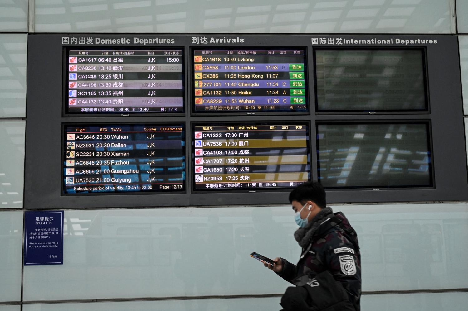 A man walks past a flight information board at Beijing’s Capital International Airport on Jan 21, 2022. A man walks past a flight information board at Beijing’s Capital International Airport on Jan 21, 2022.