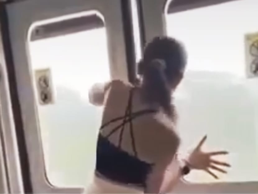 A screenshot from a video taken by a fellow commuter of Vanessa Wang trying to pull open the MRT doors.