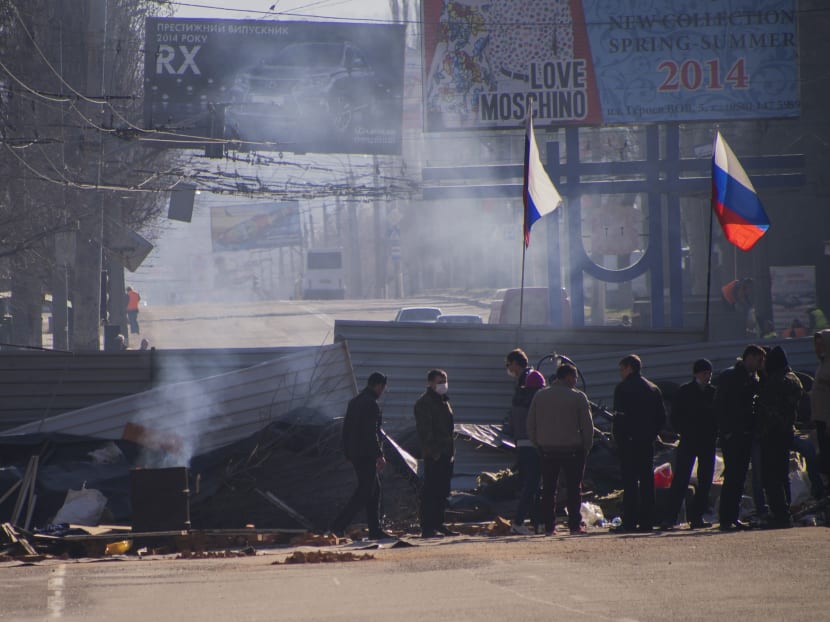 Pro-Russian activists gather behind a barricade with Russian flags in front an entrance of the Ukrainian regional office of the Security Service in Luhansk,on April 8, 2014. Photo: Reuters