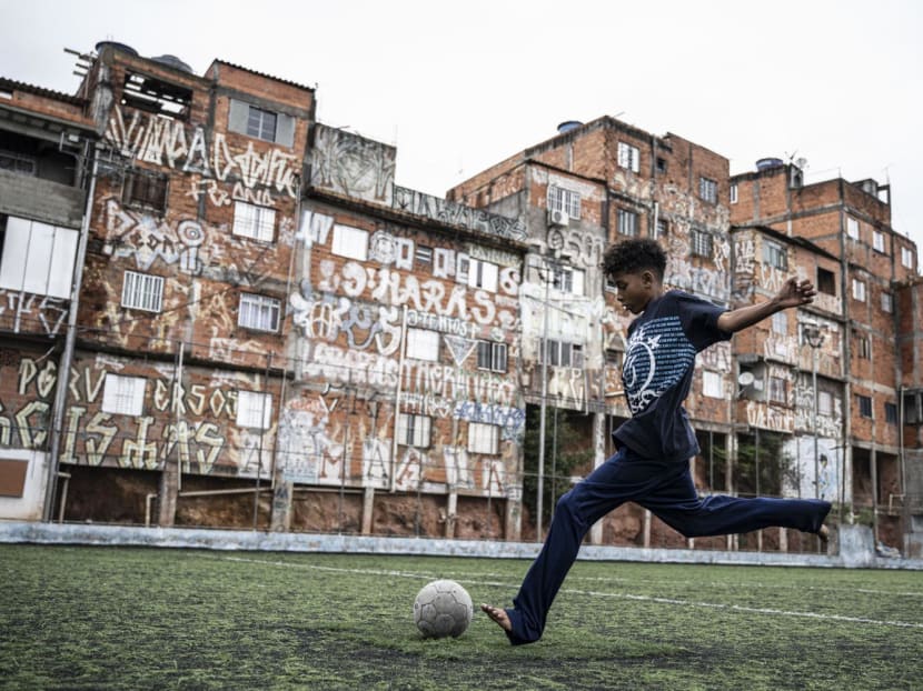 A child plays football in a field at the Morro da Lua favela, in Sao Paulo, Brazil, on Sept 30, 2022. 