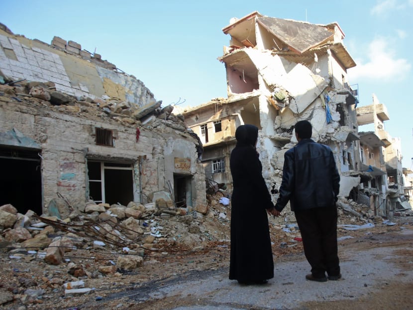 Kefa Jawish (L) and her husband Tajeddin Ahmed look a destroyed building in the Aleppo's northeastern Haydariya neighbourhood as they head to check their house for the first time in four years on December 4, 2016. Photo: AFP