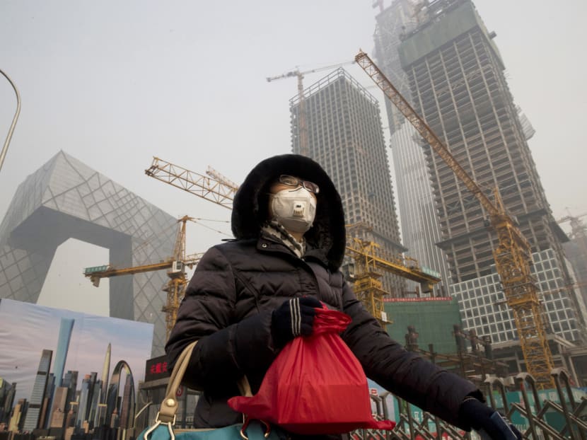 A woman wearing a mask as she walks past a construction site in Beijing. Some Chinese cities have issued an orange alert, the second-highest level after red, as pollution reached hazardous levels. Photo: AP