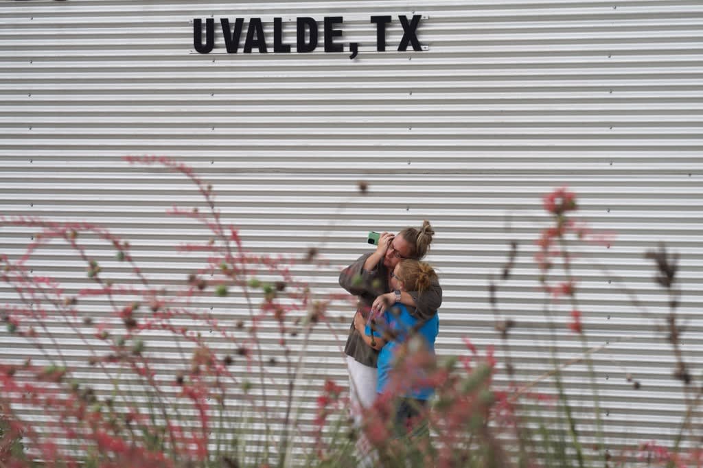 A woman cries and hugs a young girl while on the phone outside the Willie de Leon Civic Center where grief counseling will be offered in Uvalde, Texas, on May 24, 2022. 