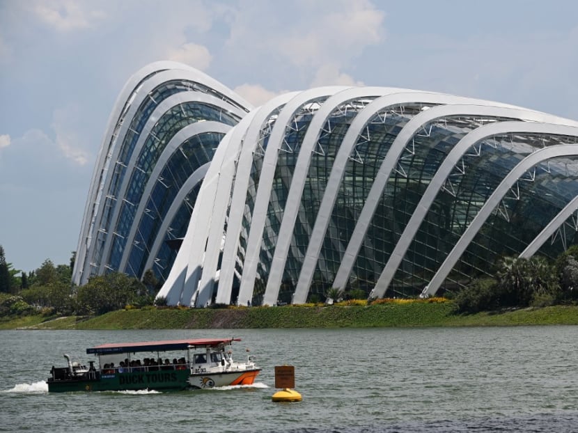 People ride in a tour boat past the Flower Domes of Gardens by the Bay along Marina Bay in Singapore on Oct 11, 2019.
