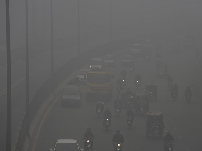 Commuters make their way along a motorway amid heavy smog conditions in Lahore on February 17, 2021.