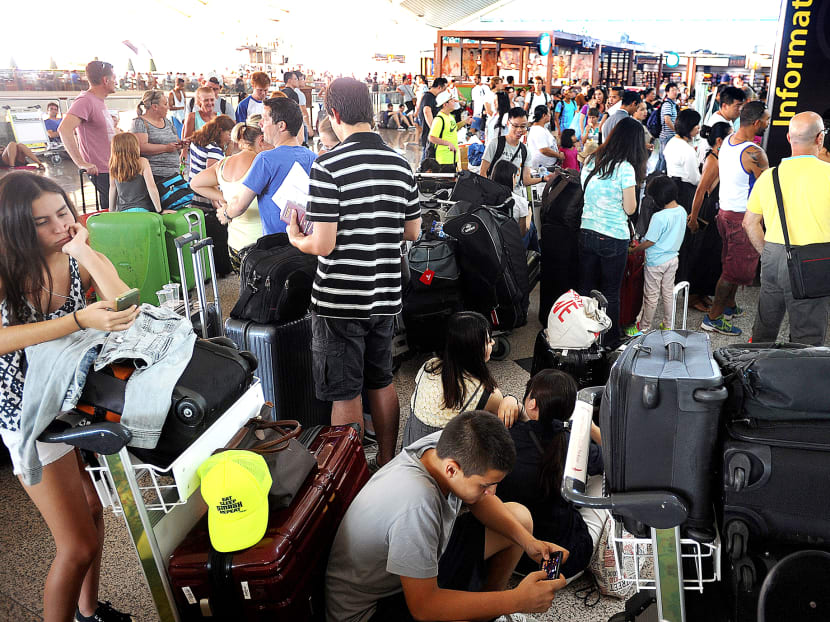 Travellers wait as flights are cancelled due to the eruption of Mount Raung in East Java, at Ngurah Rai International Airport in Bali, Indonesia, Sunday, July 12, 2015. Photo: AP