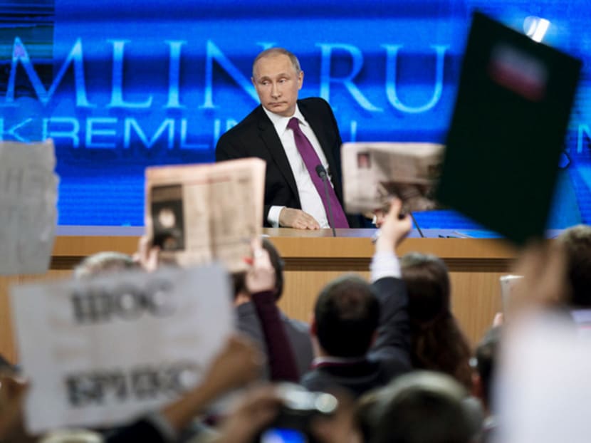 Journalists raising posters to attract Mr Putin’s attention at his annual news conference in Moscow yesterday. AP