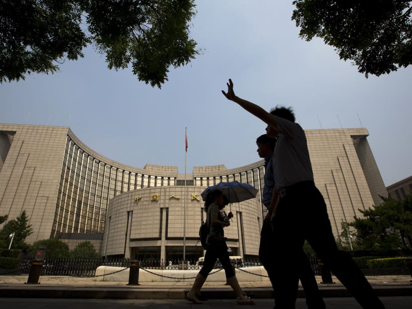 People walk past China's central bank in Beijing on Aug 11, 2015. Photo: AP