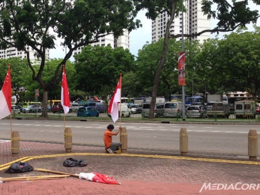 A town council worker puts up new flags after several were felled today (Aug 10). Photo: Channel NewsAsia