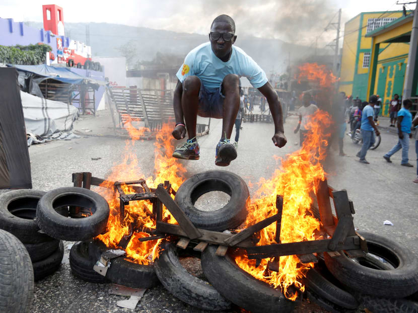 Photo of the day: A man jumps over a burning barricade during a protest against the government in the streets of Port-au-Prince, Haiti.