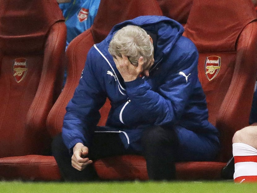 Arsene Wenger hiding his face as he watched Arsenal lose to Monaco in London on Wednesday. Photo: AP