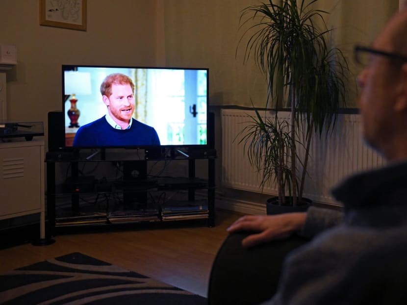 A member of the public poses in his front room in Manchester, north-west England, watching a television interview broadcast on ITV, being given by Britain's Prince Harry, Duke of Sussex on Jan 8, 2023, 