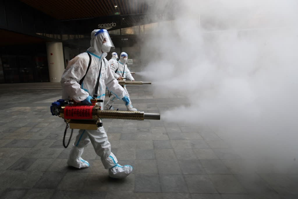 Staff members wearing personal protective equipment spray disinfectant outside a shopping mall in Xi'an in north China's Shaanxi province on Jan 11, 2022.<br />
&nbsp;