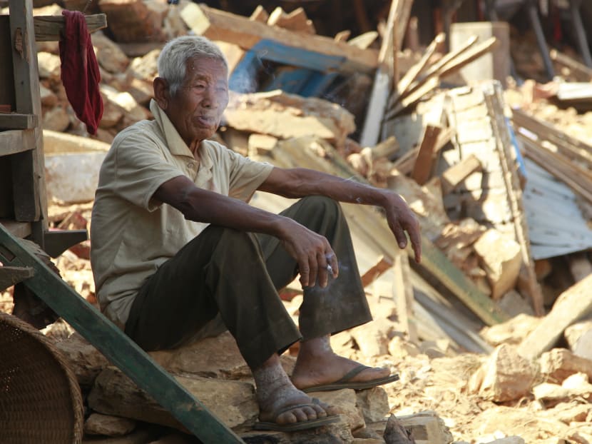 In this photo taken on Saturday, May 2, 2015, Fattha Bahadur Rana, 90, has a smoke as he sits in the rubble of his collapsed home in the destroyed village of Pokharidanda, near the epicenter of the April 25 massive earthquake, in the Gorkha District of Nepal. Photo: AP