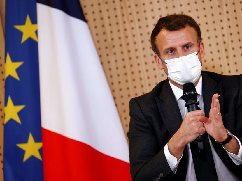 French President Emmanuel Macron, wearing a protective face mask, gestures as he talks to medical staff members during a visit of a child psychiatry department in a hospital in Reims, northern France on April 14, 2021.