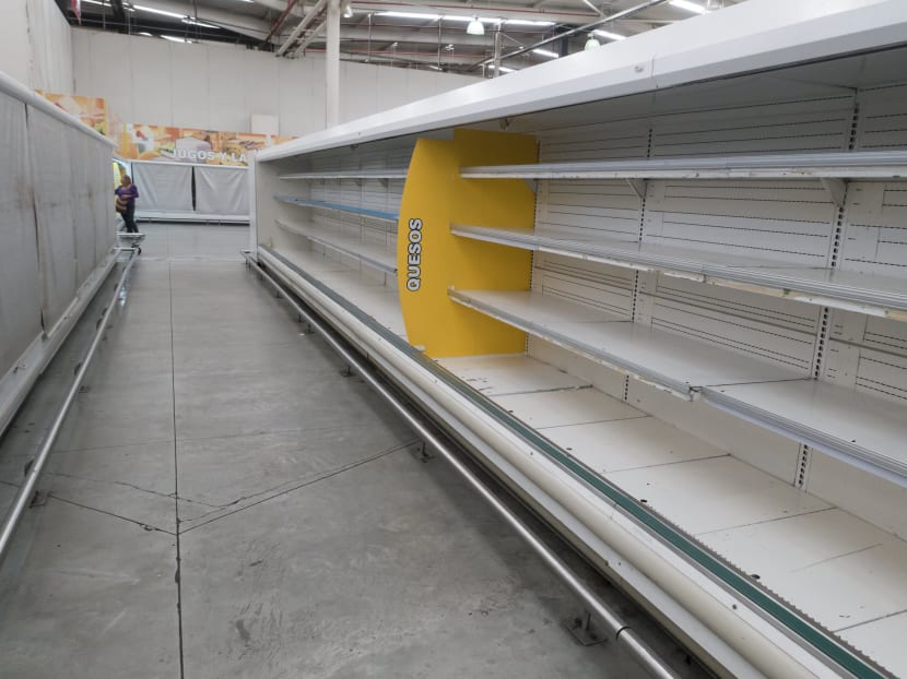 A woman is pictured past empty refrigerator shelves at a Makro supermarket in Caracas August 4, 2015. Photo: Reuters