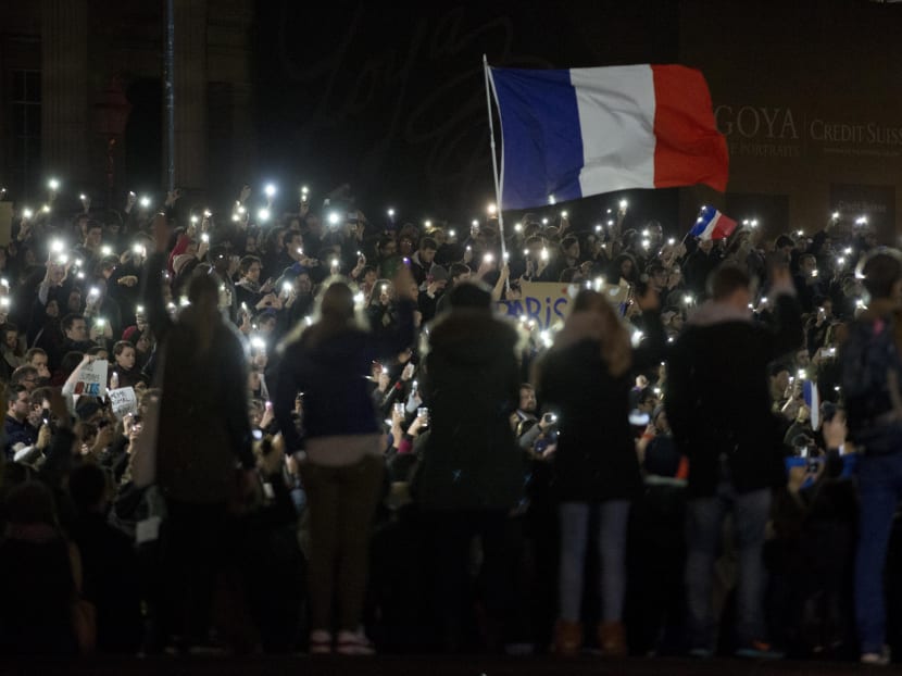 People, many of whom are French, hold up their lit phones as they take part in a vigil in solidarity with France after the deadly attacks in Paris, in Trafalgar Square, London, Nov 14, 2015. Photo: AP