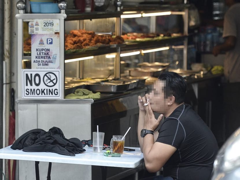 A man smokes outside an eatery in Petaling Jaya, Malaysia.