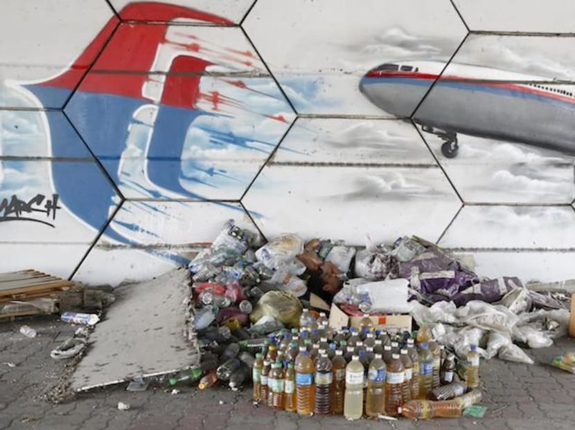 A man sleeps under graffiti depicting the missing Malaysia Airlines flight MH370 on the one year anniversary of its disappearance in Kuala Lumpur, March 8, 2015. Photo: Reuters