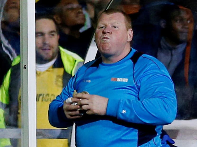 Sutton United's substitute Wayne Shaw eating the pie during the match. Photo: Reuters