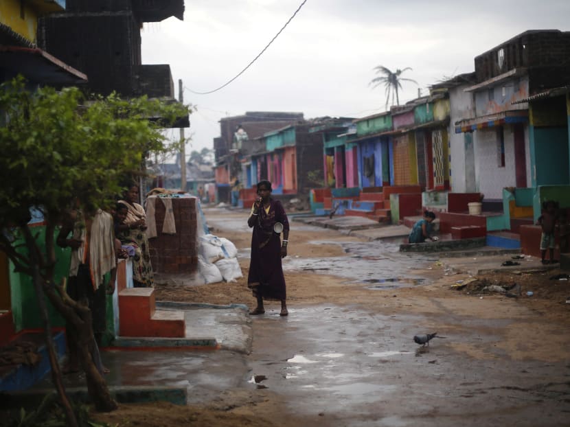A woman brushes her teeth as she stands outside her cyclone-damaged house in the eastern Indian state of Odisha.