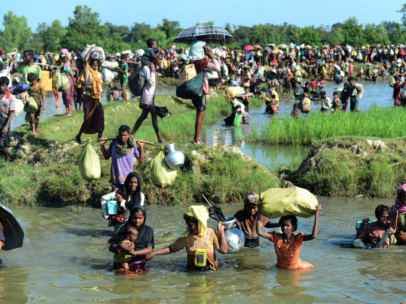 In this file photo taken on Oct 16, 2017, Rohingya refugees walk through a shallow canal after crossing the Naf River in Palongkhali near Ukhia, as they flee violence in Myanmar to reach Bangladesh.