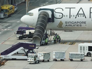 Airport officials standing near the Singapore Airlines aircraft for flight SQ321 parked on the tarmac after an emergency landing at Suvarnabhumi International Airport in Bangkok, Thailand, May 22, 2024.