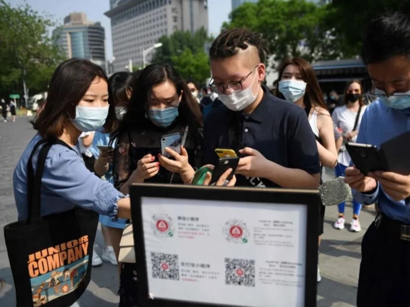 People use QR codes required to prove their health and travel status before being allowed to enter a shopping mall in Beijing.