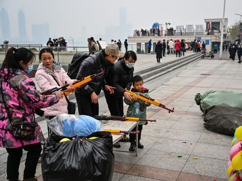 People aim to burst balloons with toy guns at a stall along the Yangtze River in Wuhan, in China's central Hubei province, on Jan 22, 2023. 