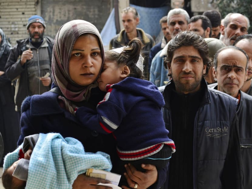 Residents queue up to receive humanitarian aid at the Palestinian refugee camp of Yarmouk, in Damascus. Photo: Reuters