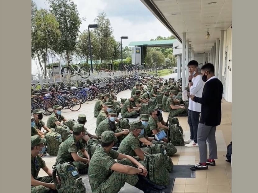 A Singapore Armed Forces (SAF) commander wearing a white shirt was seen addressing a group of SAF serviceman with his mask tucked under his chin.