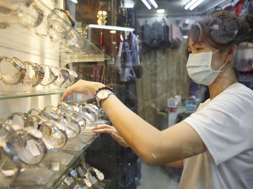 Ms Amy Tio, a bag and watch shop owner, arranges watches in her store on May 13, 2022.