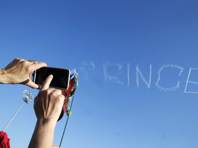 A festival-goer takes a photo as a skywriter spells "Prince," in honor of pop music icon Prince, at the New Orleans Jazz and Heritage Festival in New Orleans, Saturday, April 23, 2016. Prince died Thursday at the age of 57.  Photo: AP