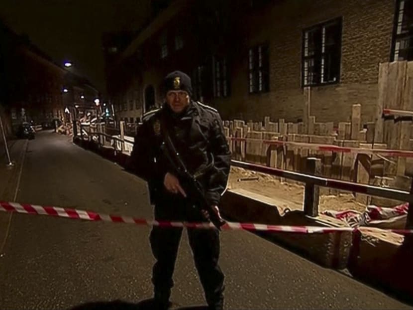 This image from TV2 via Associated Press News video shows armed police guard behind police tape near a synagogue where police reported a shooting in downtown Copenhagen, Denmark, Sunday, Feb. 15, 2015.  One person was shot in the head and two police officers were shot in the arms and legs, police said. Photo: AP