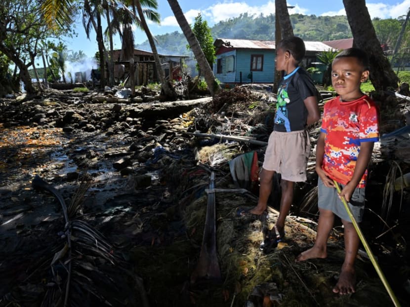 This picture taken on Dec 13, 2022 shows youths outside their beachfront houses threatened by coastal erosion in the town of Veivatuloa in Fiji. 